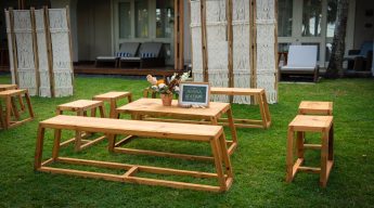 Henna station setup for wedding or event with low wooden benches, tables, and macrame bohemian room dividers on a lawn.