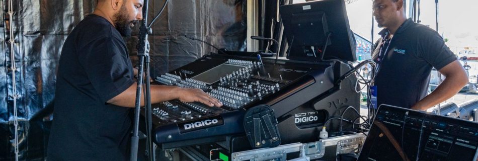 Sound engineers working on a Digico SD digital mixing console at a live event.