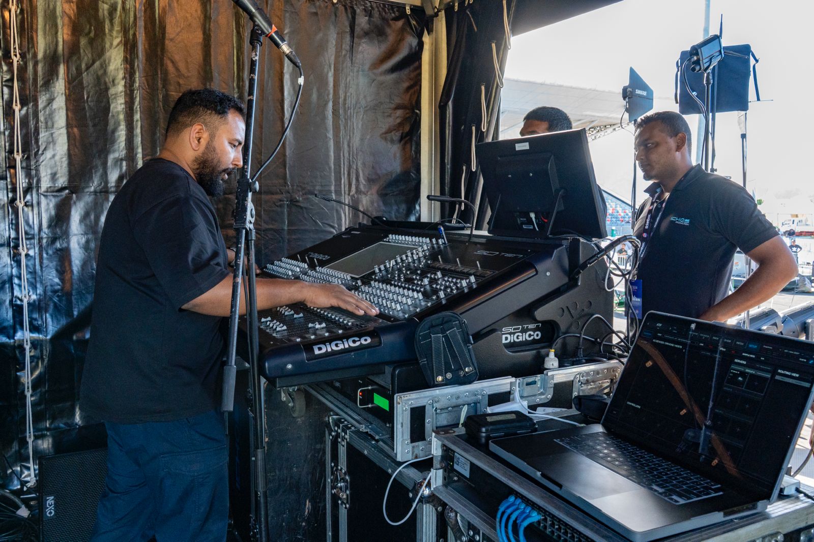 Sound engineers working on a Digico SD digital mixing console at a live event.