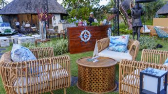 Daytime view of an outdoor lounge area with woven rattan chairs, a wood ship-themed bar, and nautical-themed pillows and decorations.