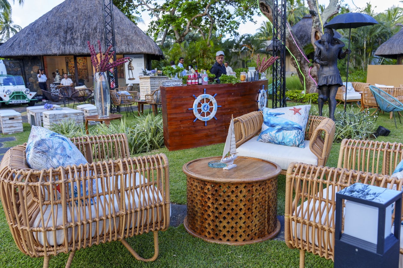 Daytime view of an outdoor lounge area with woven rattan chairs, a wood ship-themed bar, and nautical-themed pillows and decorations.