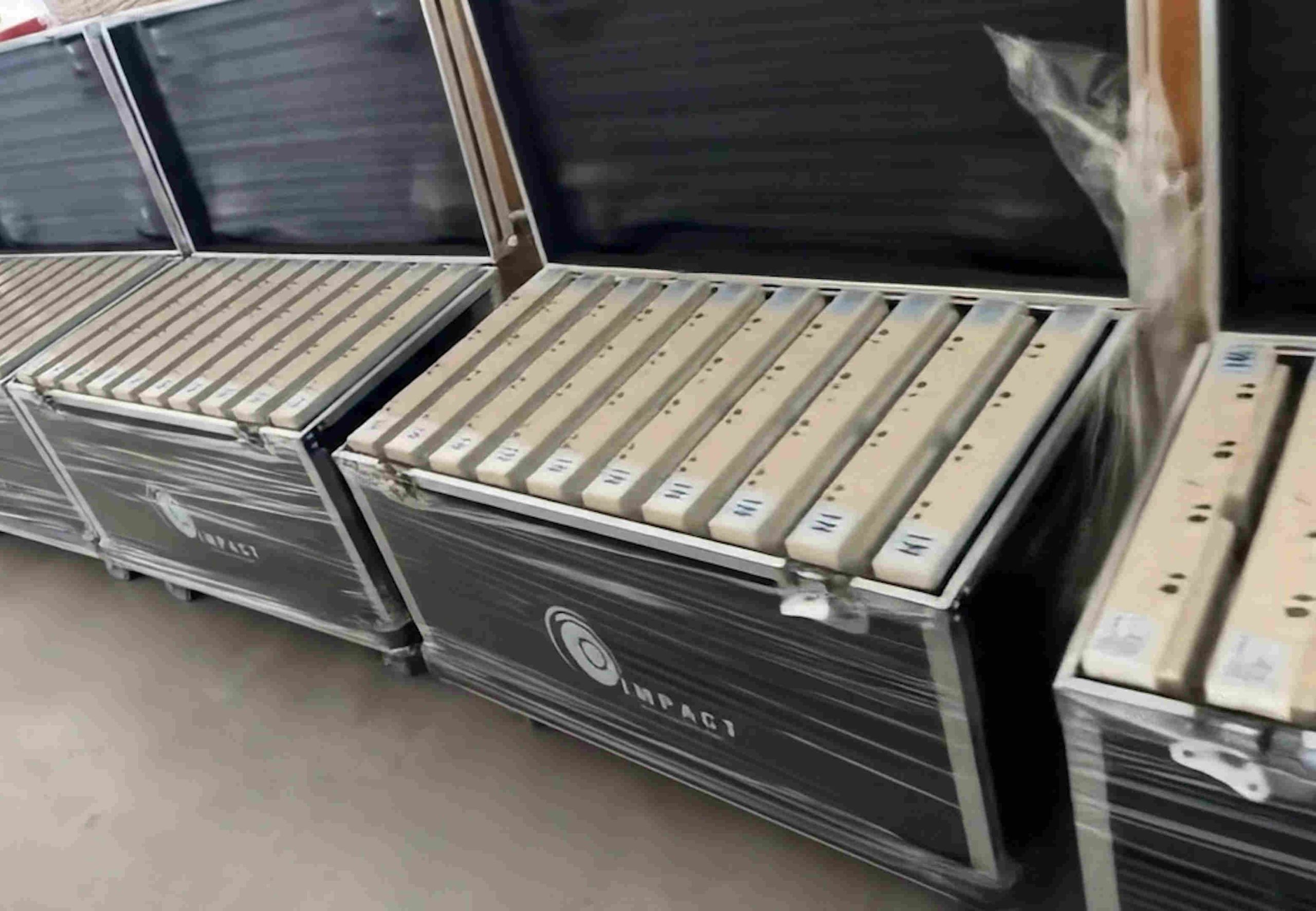 Stacked open cases with Impact logos hold multiple cream-colored power strips organized neatly, evoking a sense of precision and readiness.