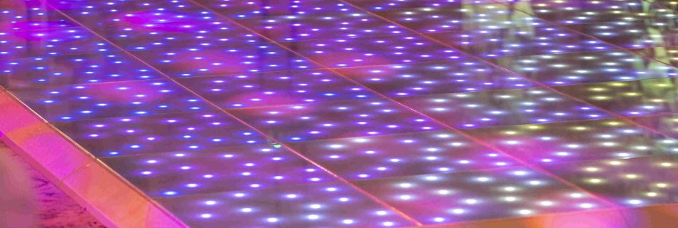 Sparkling LED dance floor with a grid pattern emits vibrant blue and pink lights, creating a lively and festive atmosphere.